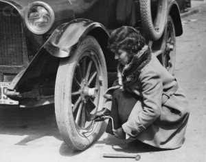 Young Woman Fixing Flat On Old Car.